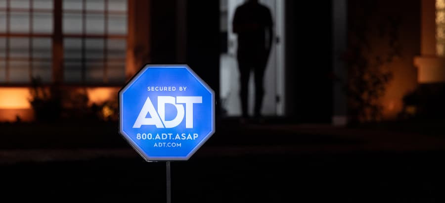 Bright ADT home security sign in front of a home at night.